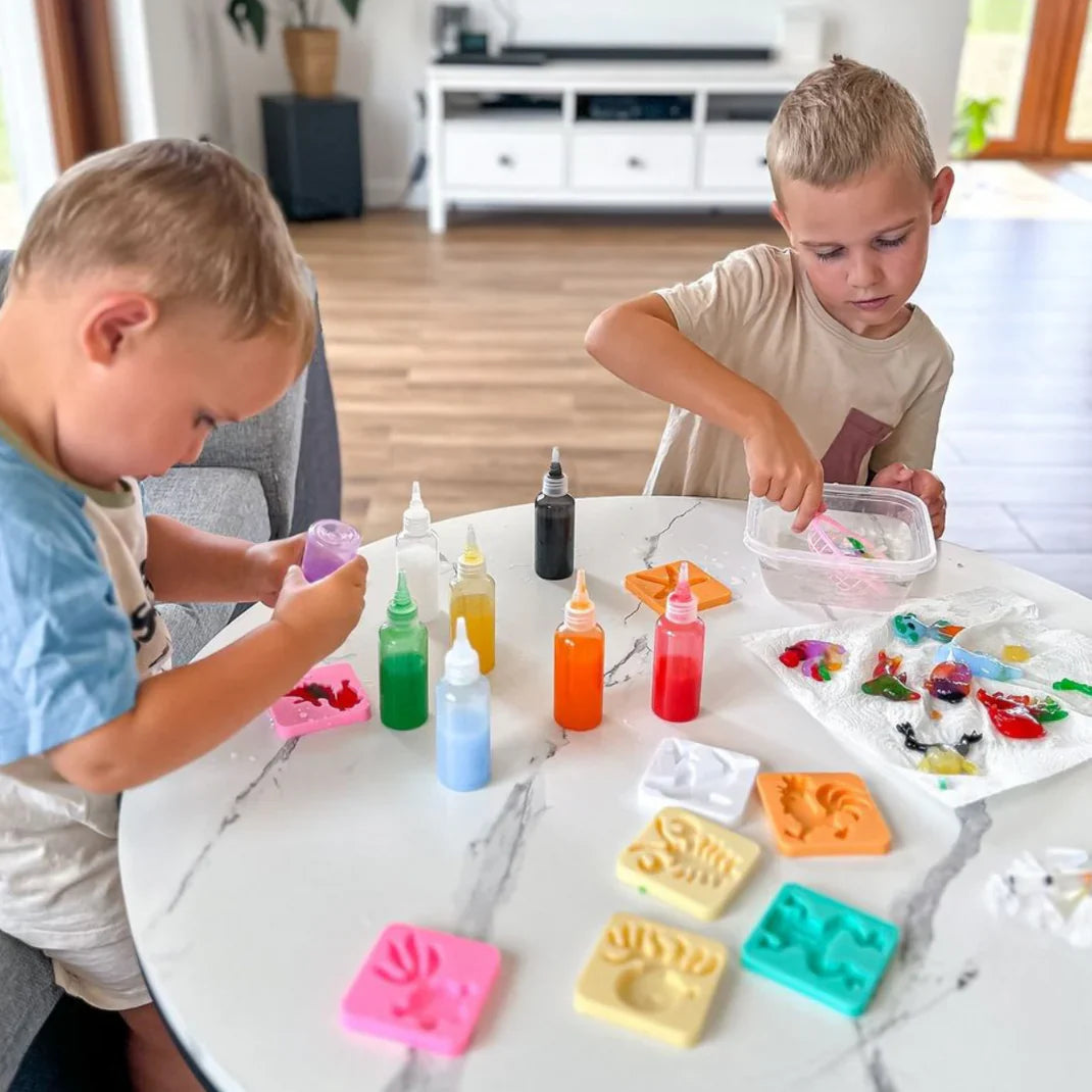 A child's hands squeezing colored gel into a mold above a bowl of water